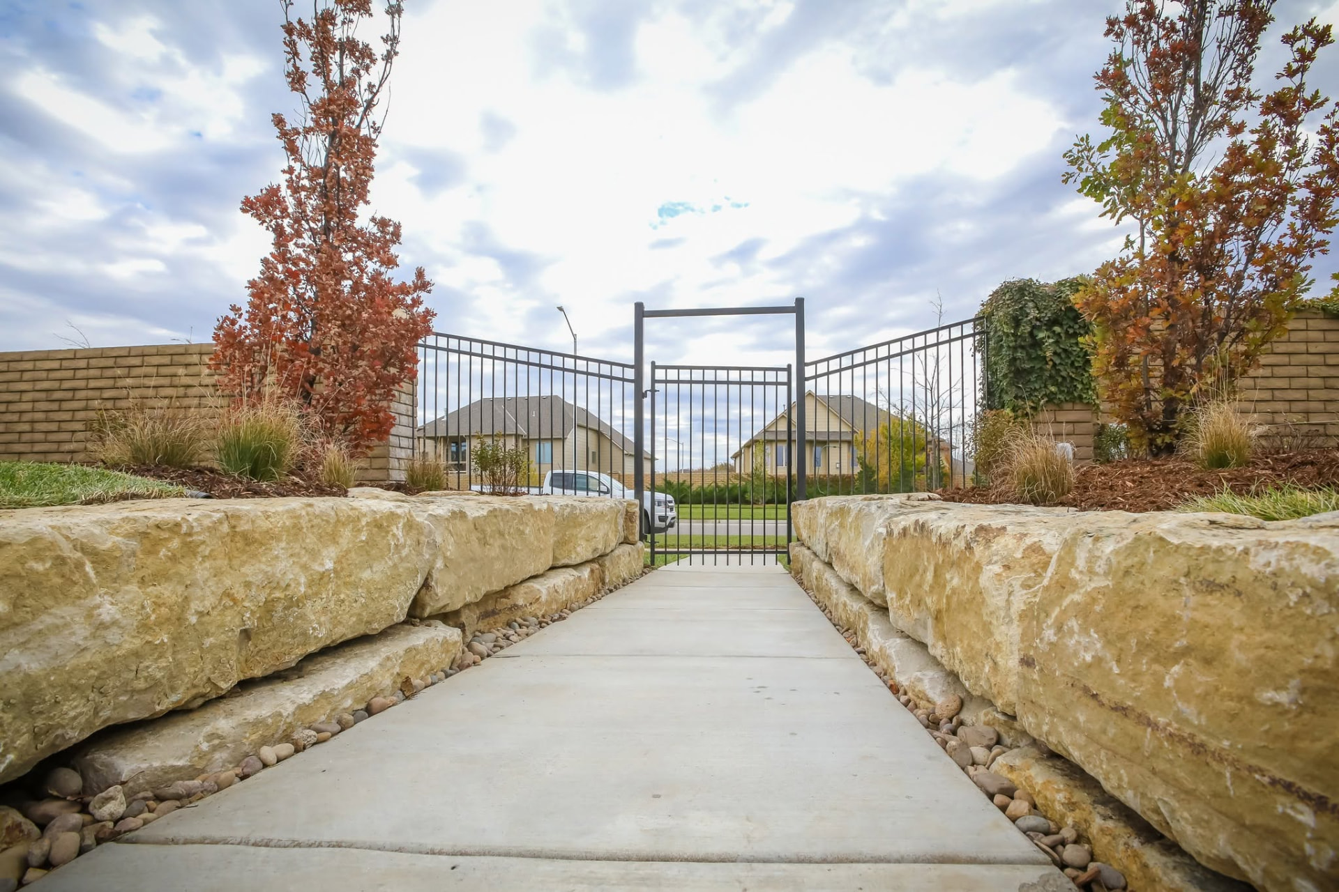 Walkway lined with large natural stone boulders leading to a garden gate