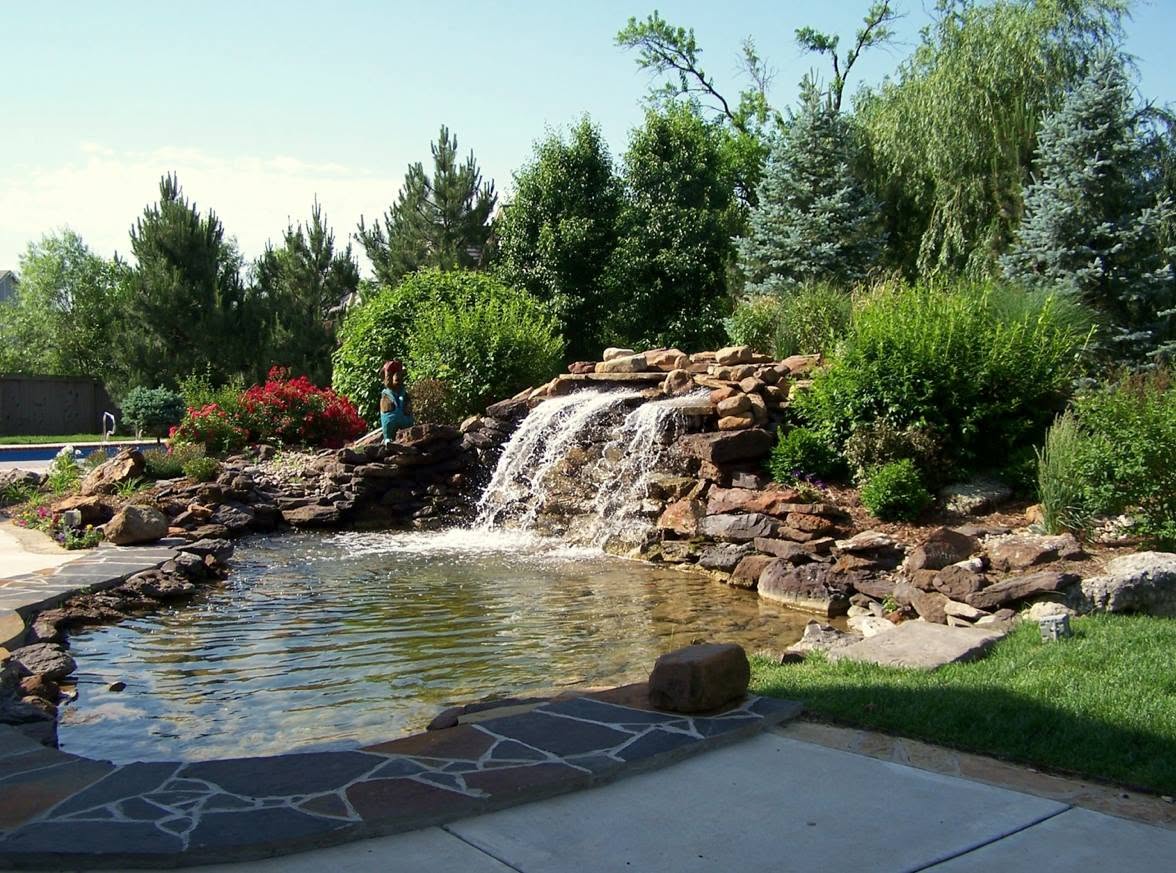 Stone waterfall spilling into a pond surrounded by plantings